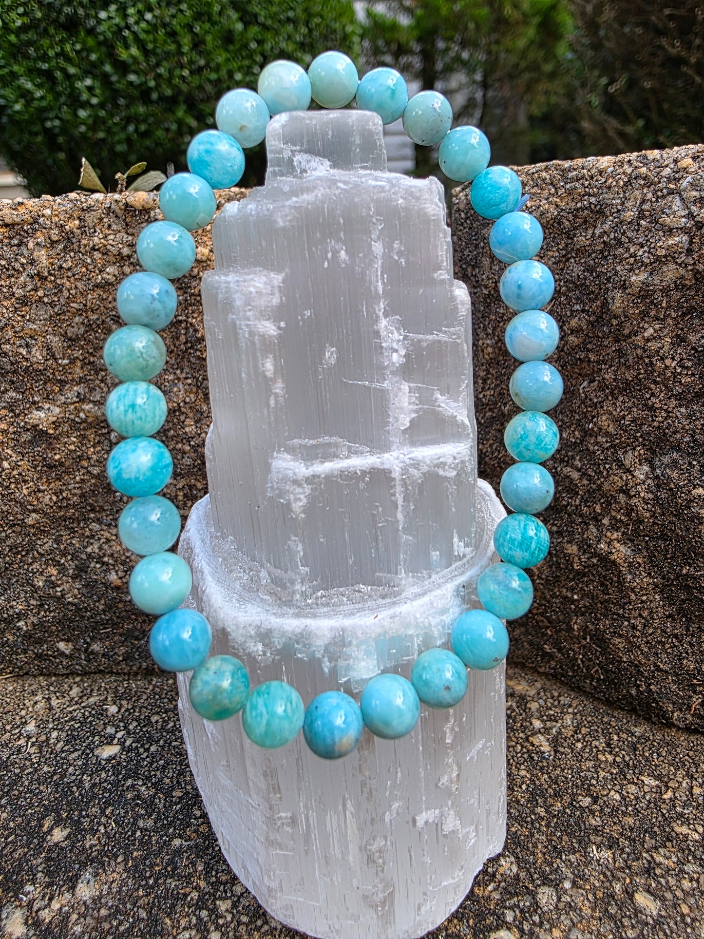 Larimar bracelet featuring round Caribbean blue beads reminiscent of the ocean, displayed on a selenite tower