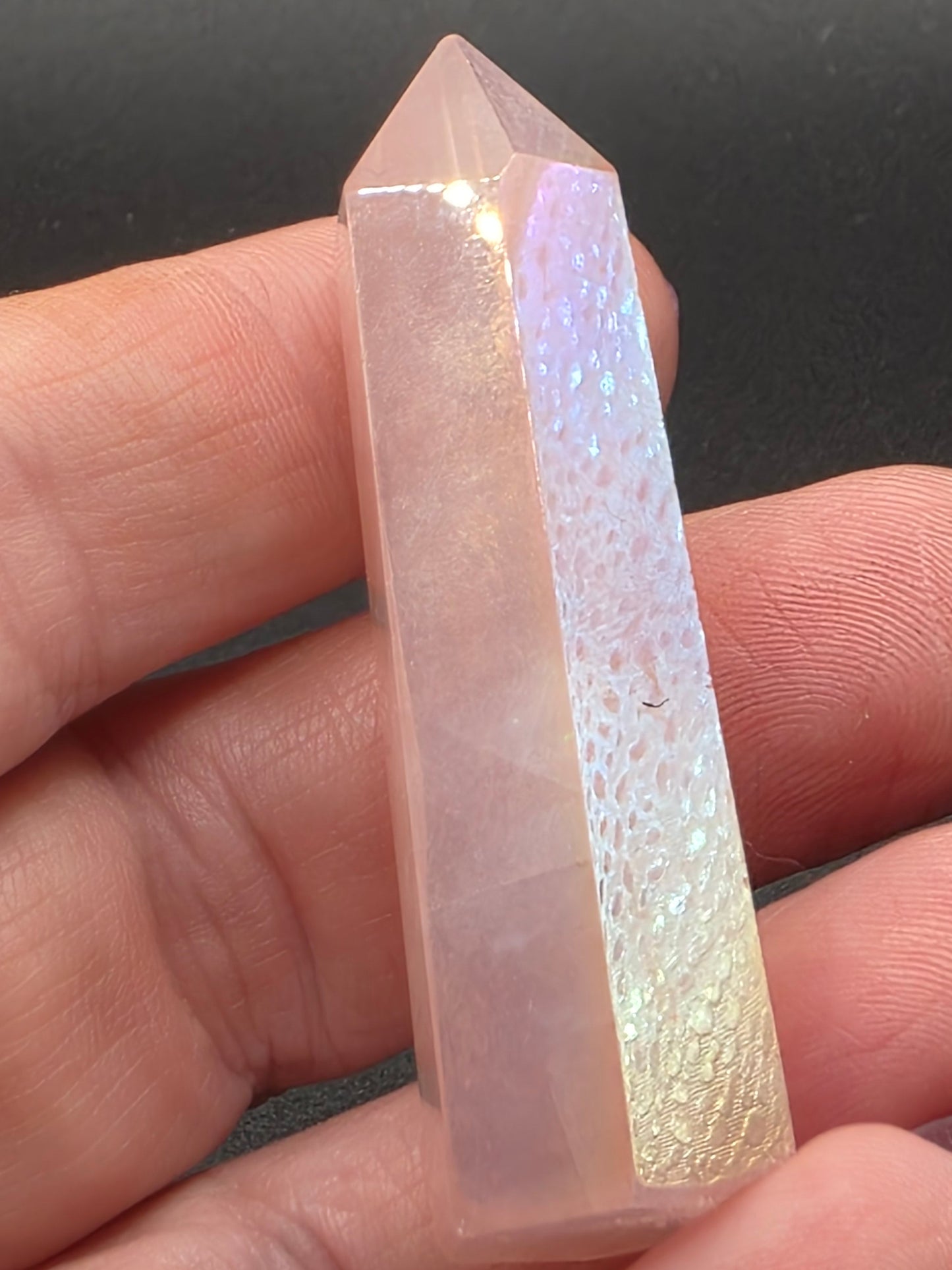 Aura Rose Quartz tower with pink hue and iridescent shimmer held in hand.