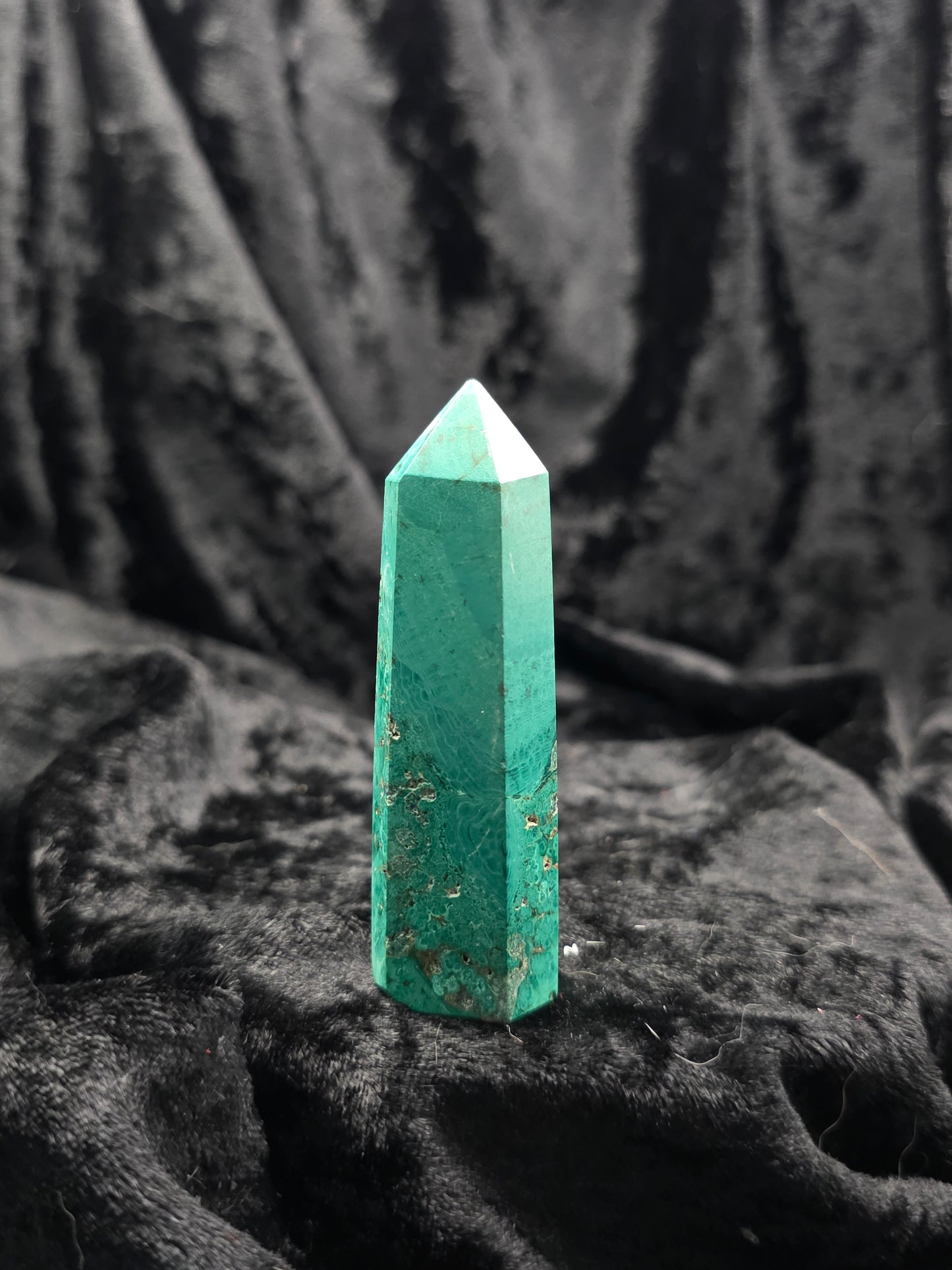 Chrysocolla with Malachite tower, 2.8 inches tall, vibrant teal and green hues with circular banding and a minor chip on the tip, photographed on hand under natural light.