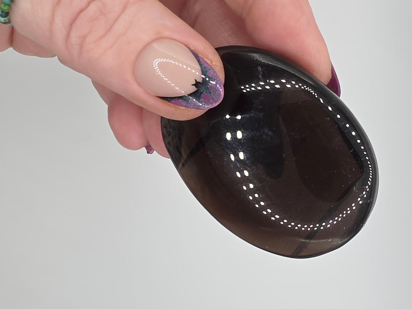 Smoky Quartz palm stone with translucent brown hue held in hand.