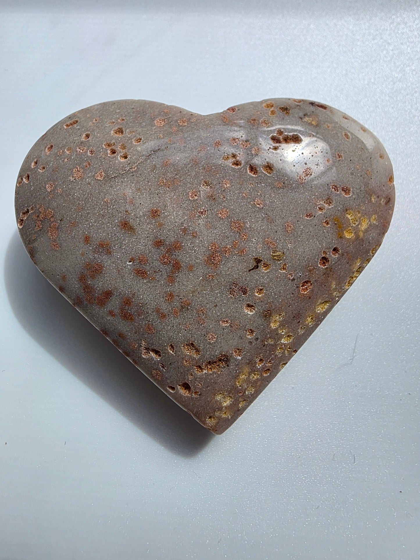 Full view of a Sunstone heart crystal on a white background, featuring metallic copper flecks and smooth polish.