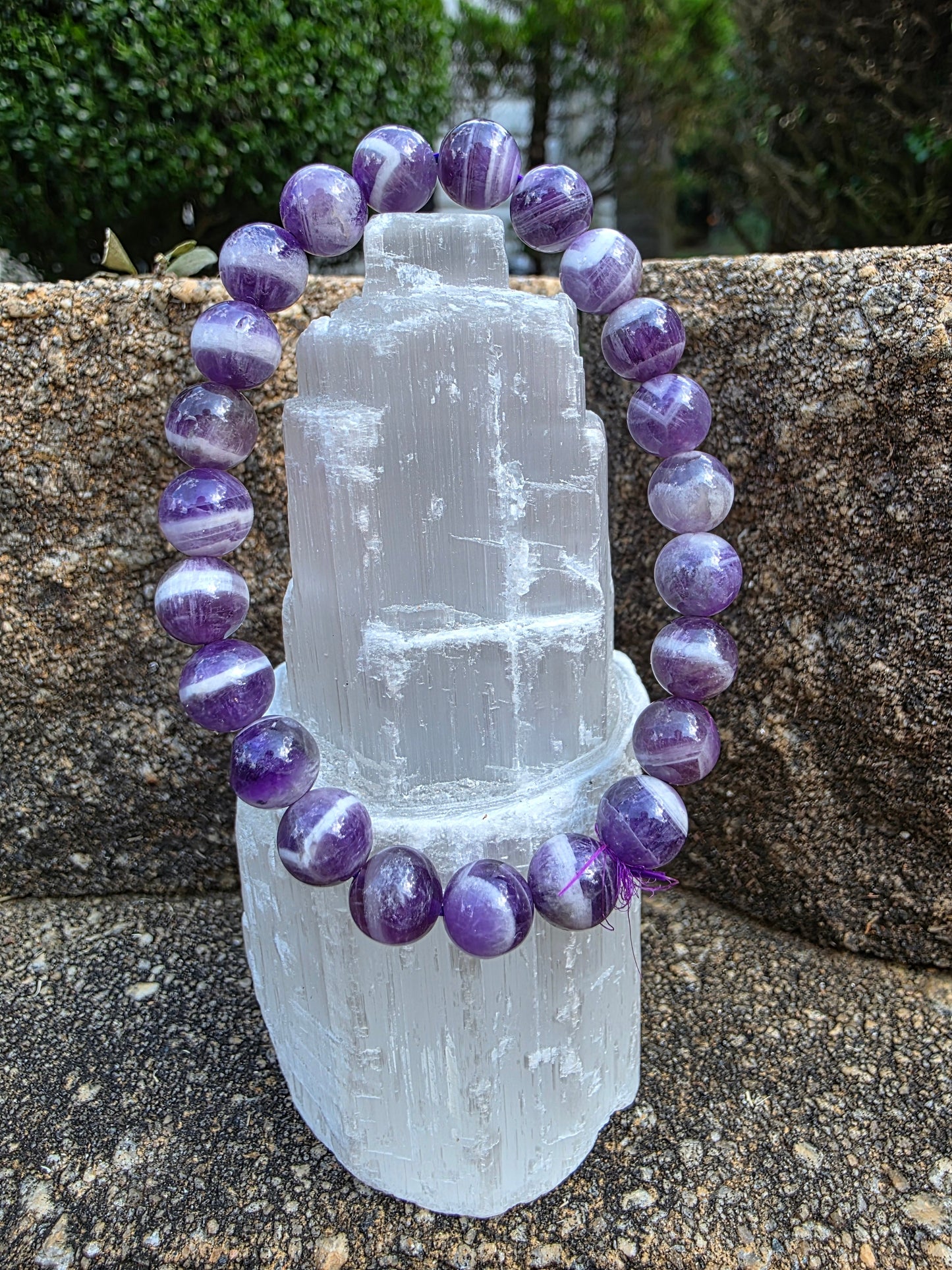 Dream Amethyst bracelet featuring 8mm beads with swirling purple and white bands, displayed on a selenite tower; this chevron amethyst supports intuition and calm.
