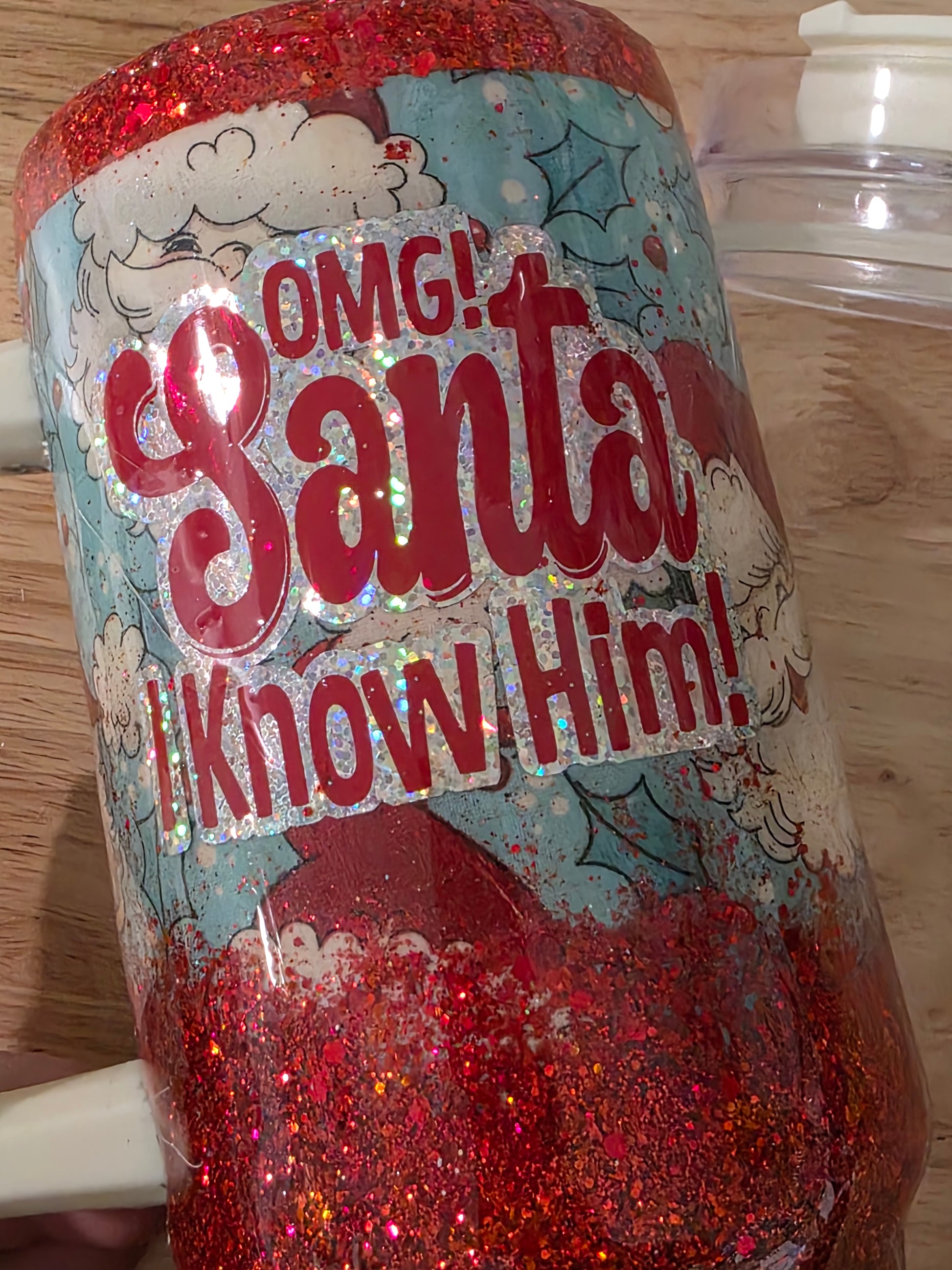 Close-up of holographic and red layered vinyl reading OMG Santa I Know Him on glittered tumbler.