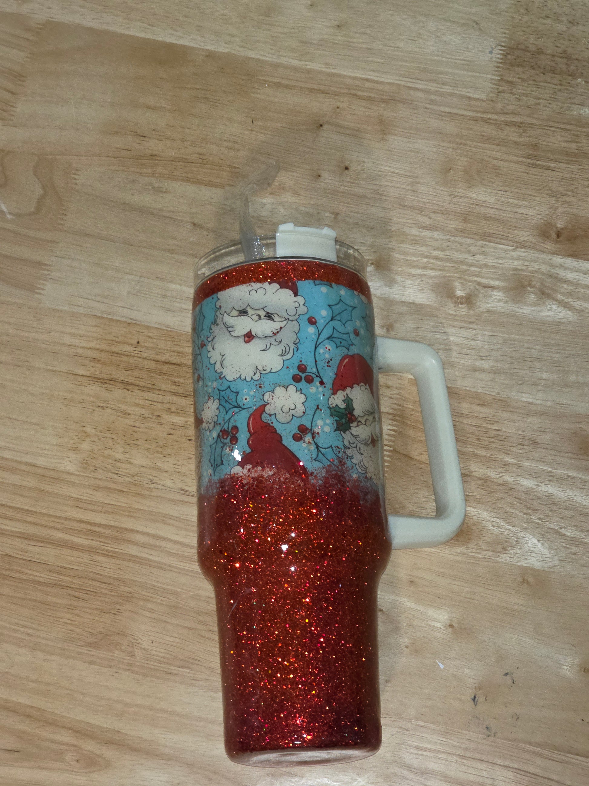 40oz handled holiday tumbler with vintage Santa fabric and red glitter ombré, shown on wooden table.