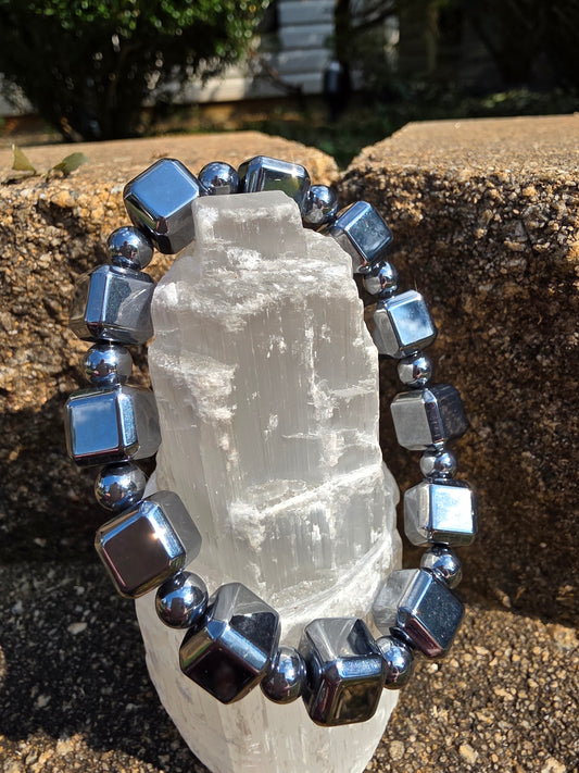 Terahertz cube bracelet featuring reflective metallic silver cube beads alternated with small round spacers, wrapped around a selenite tower on natural stone. This high-frequency stone is said to enhance energy flow, relieve fatigue and provide EMF protection.