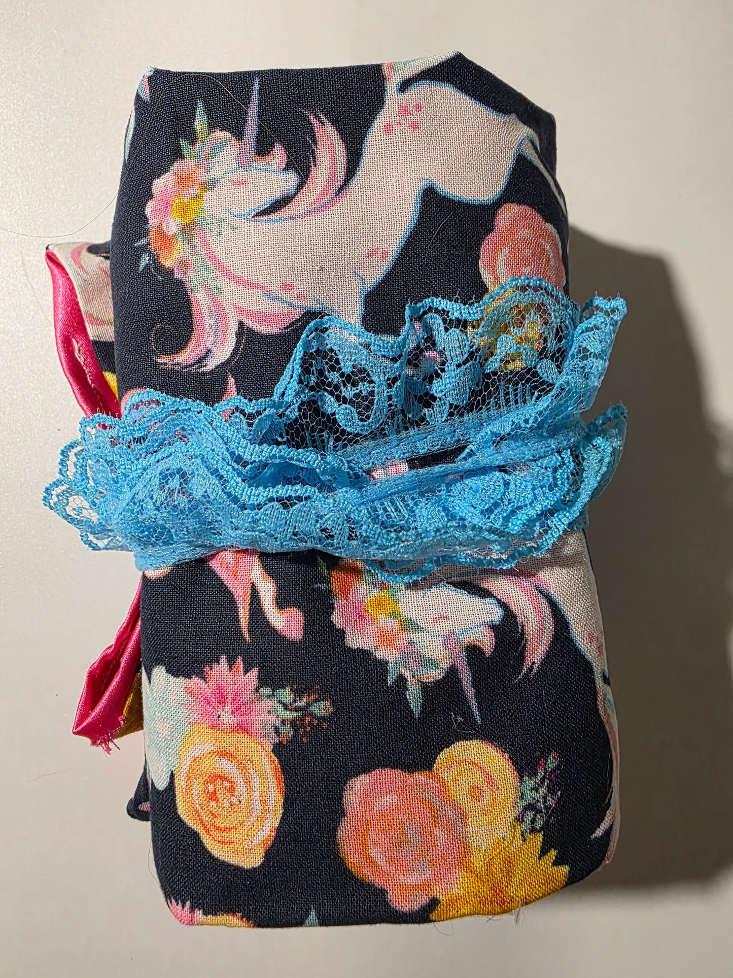 Handmade tarot wrap featuring navy fabric with pastel unicorns and floral designs, pink satin lining, turquoise lace tie, and selenite stick for cleansing and protection.