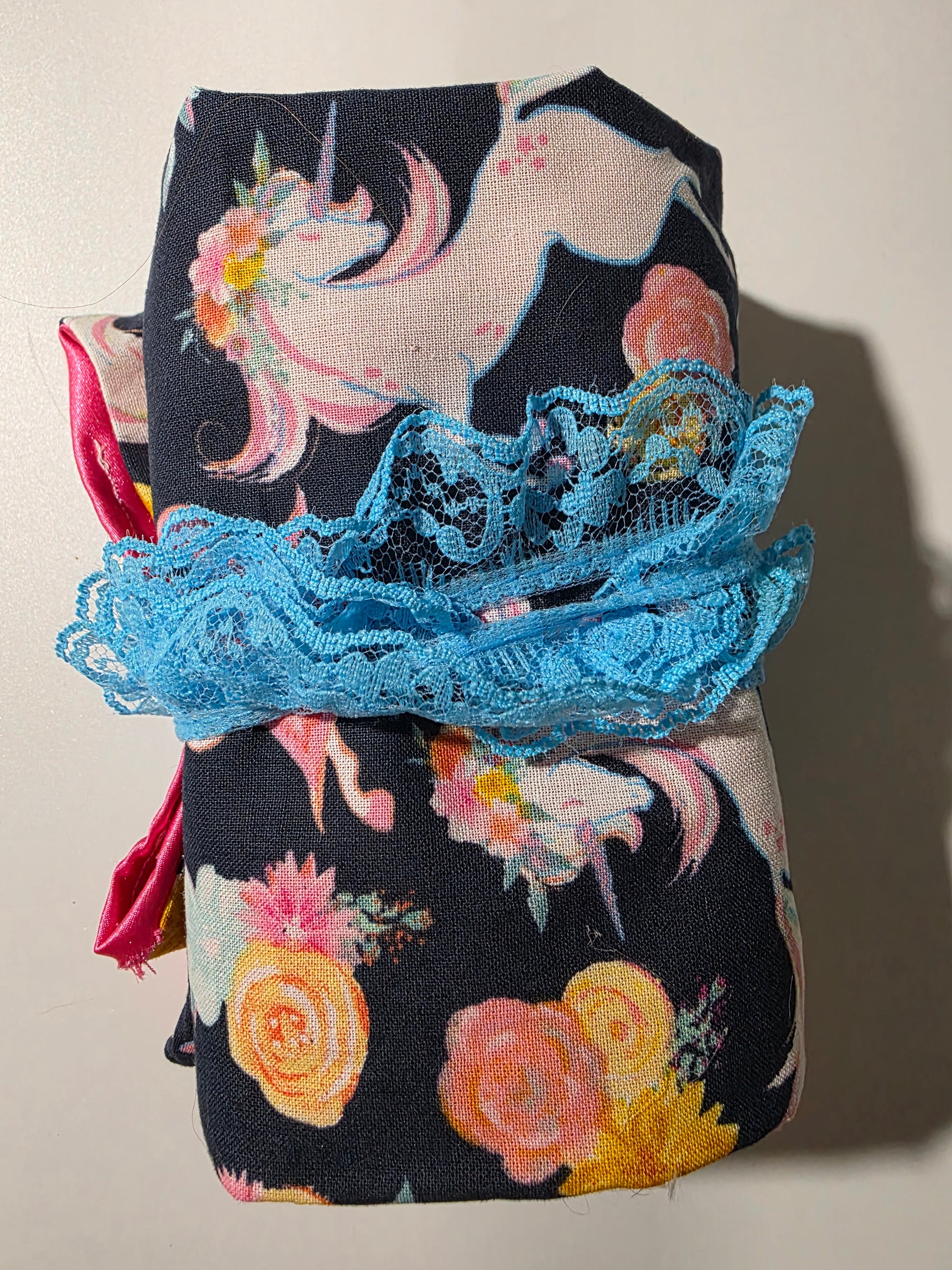 Handmade tarot wrap featuring navy fabric with pastel unicorns and floral designs, pink satin lining, turquoise lace tie, and selenite stick for cleansing and protection.