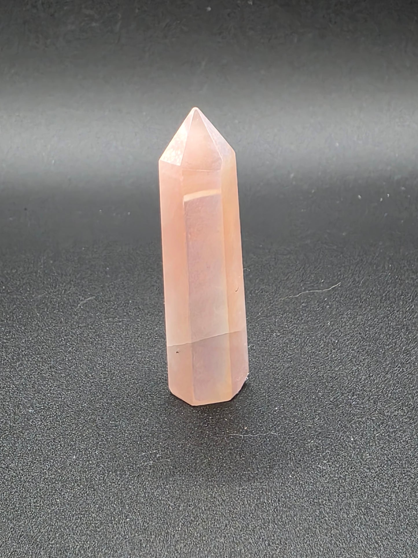 Standing Aura Rose Quartz tower on black background showing soft glow.