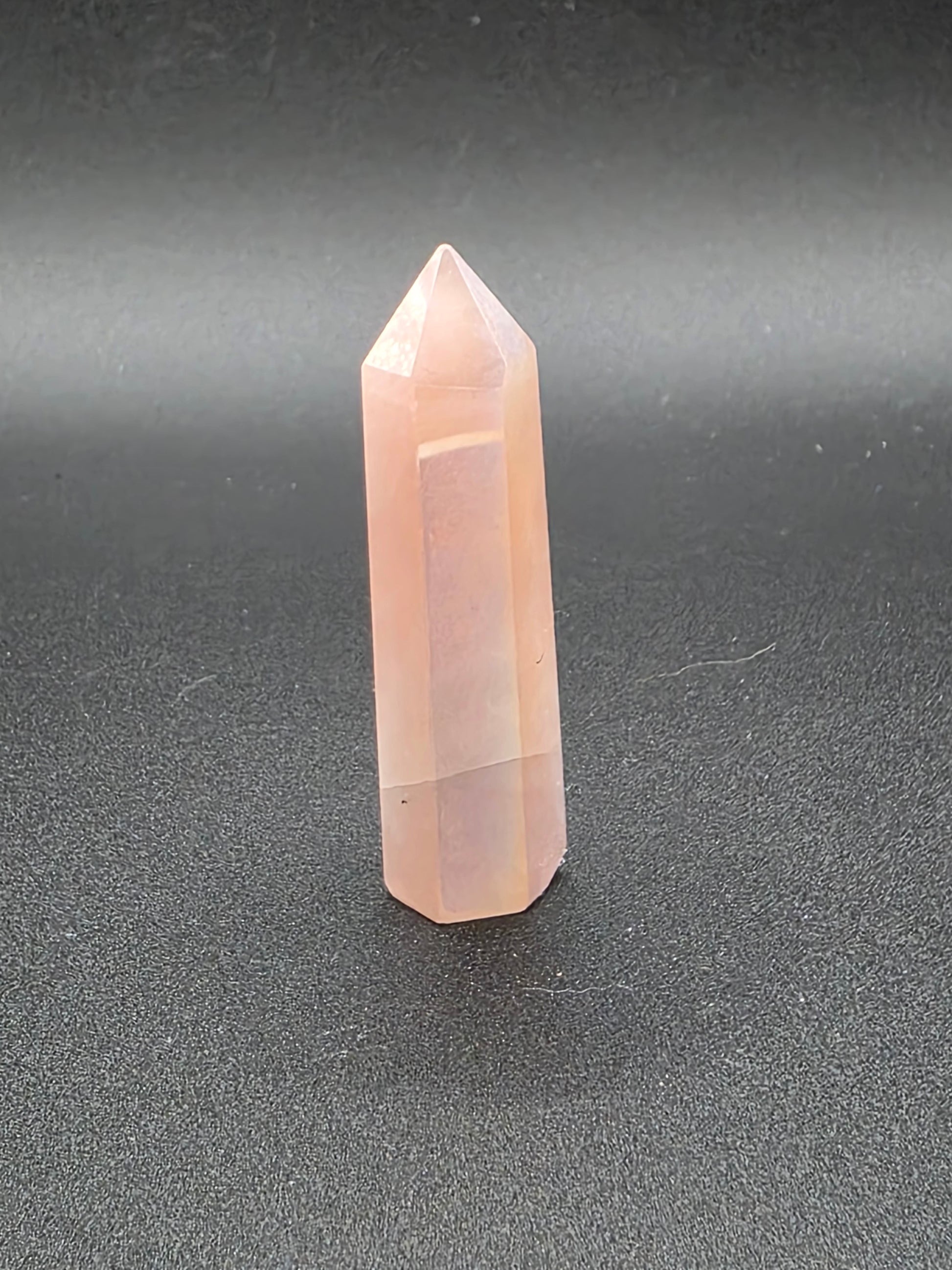 Standing Aura Rose Quartz tower on black background showing soft glow.