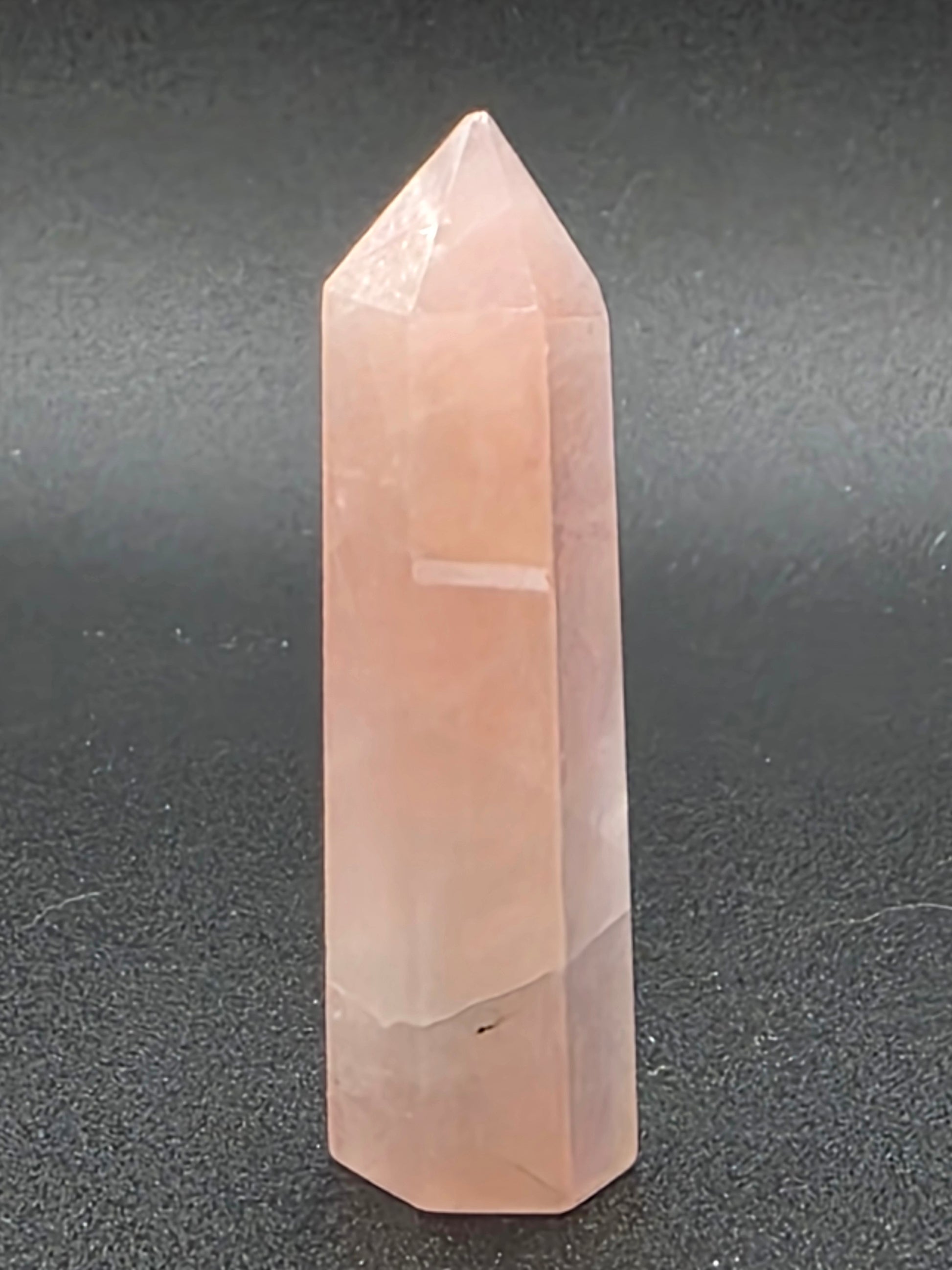 Close-up of Aura Rose Quartz tower displaying rainbow surface reflection and smooth polish.