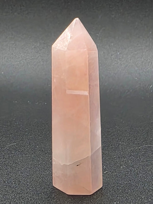 Close-up of Aura Rose Quartz tower displaying rainbow surface reflection and smooth polish.