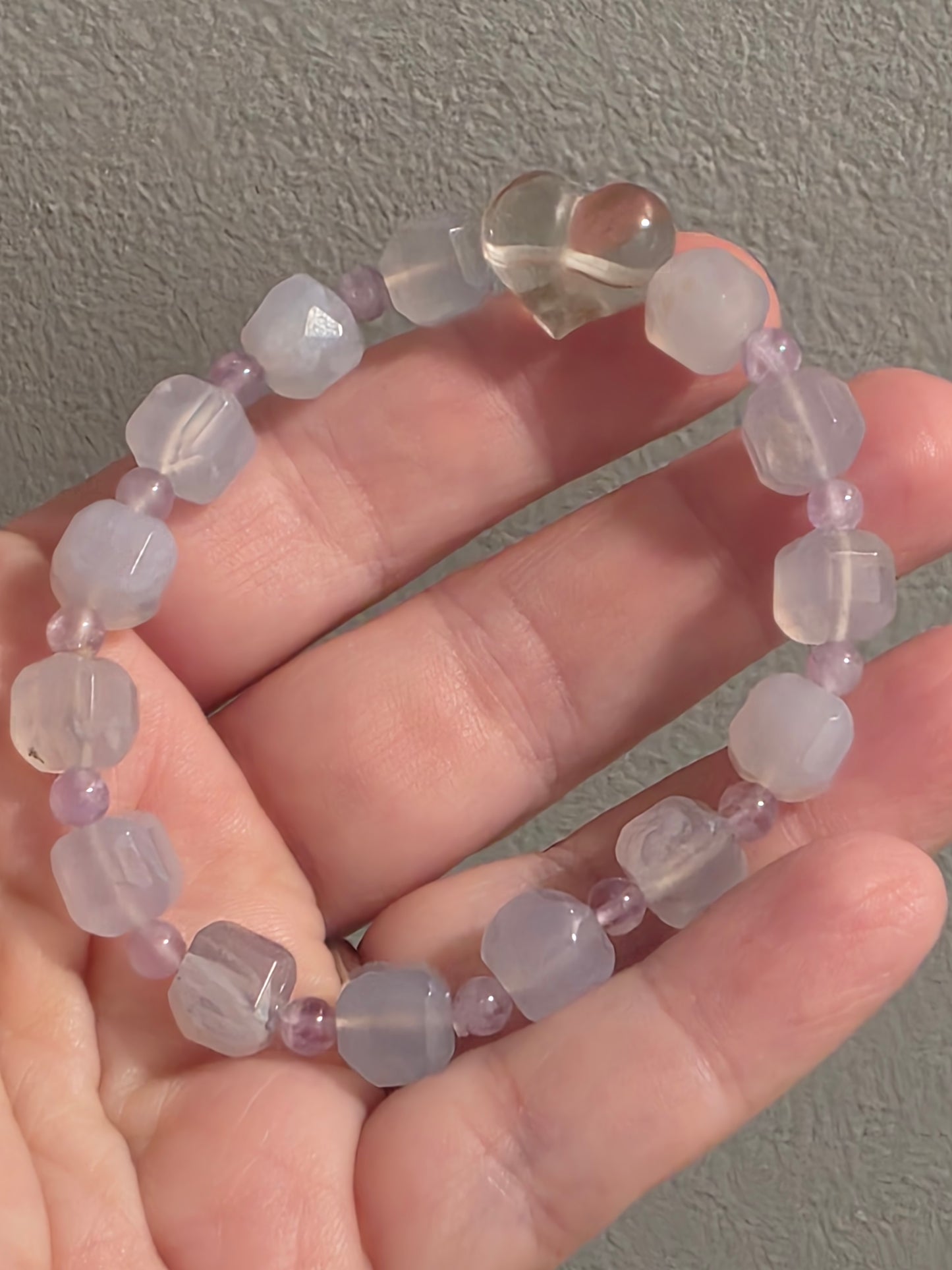 Blue Lace Agate and Amethyst cube-cut bracelet with Clear Quartz heart accent, displayed in hand for scale and color detail.