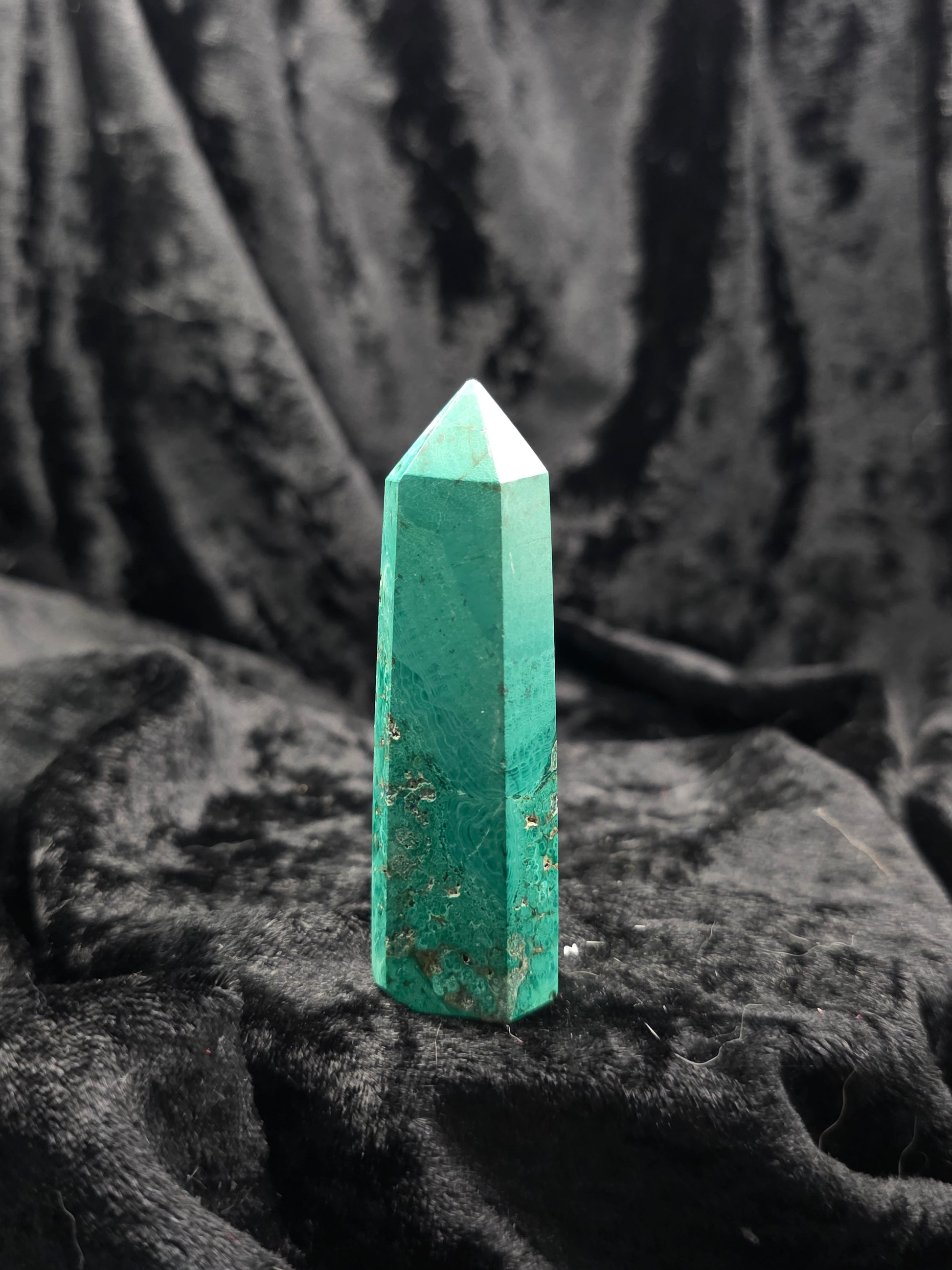 Chrysocolla with Malachite tower, 2.8 inches tall, vibrant teal and green hues with circular banding and a minor chip on the tip, photographed on hand under natural light.