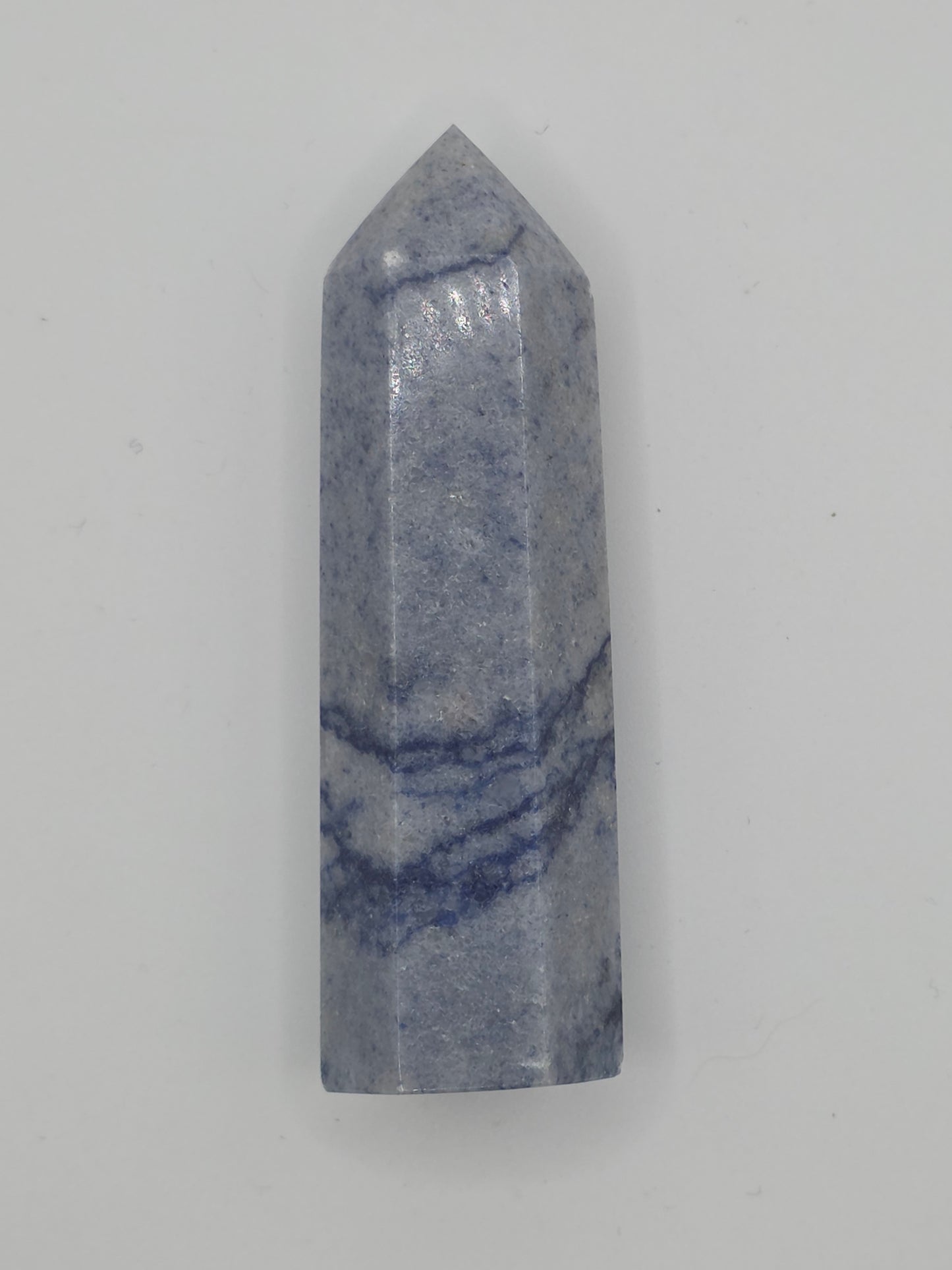 Dumortierite tower with soft indigo and gray banding, standing upright on a white background.