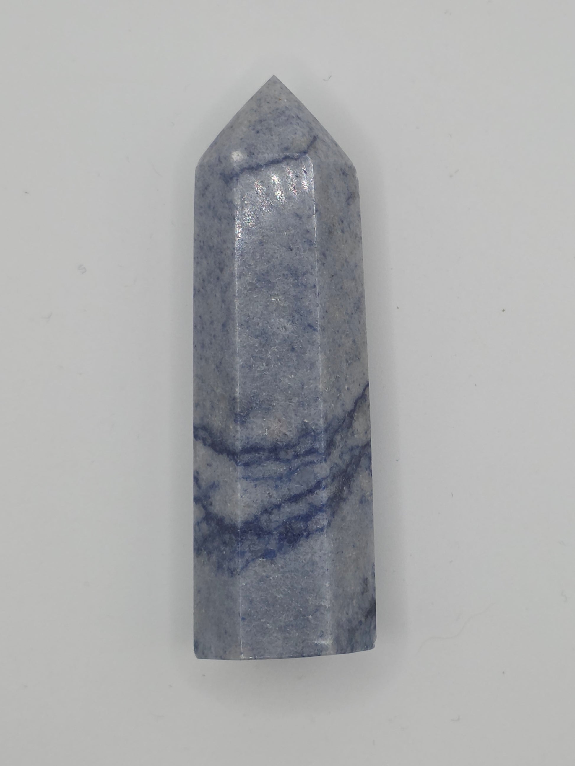 Dumortierite tower with soft indigo and gray banding, standing upright on a white background.