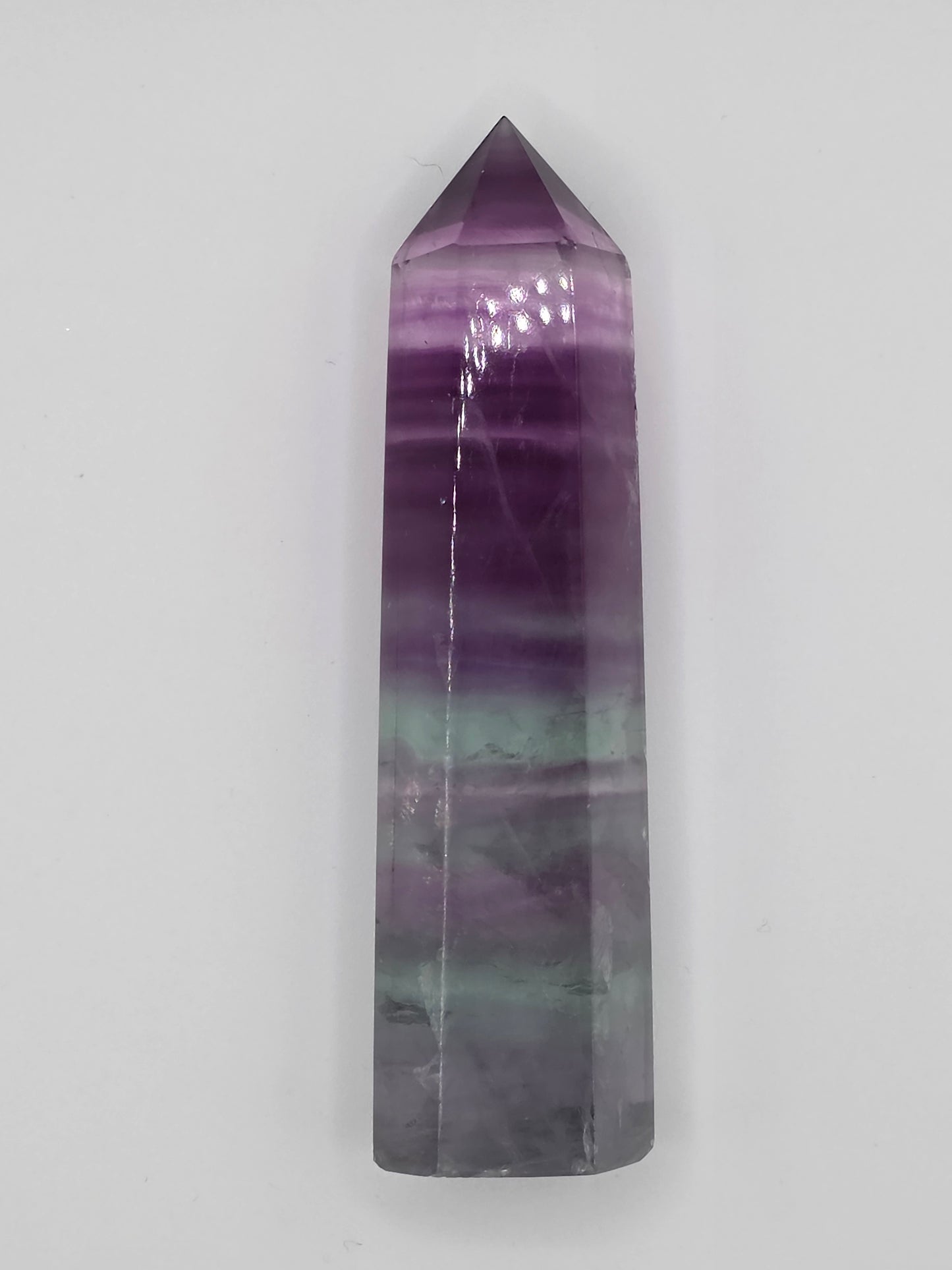 Fluorite tower with violet and teal banding, upright on a white background.