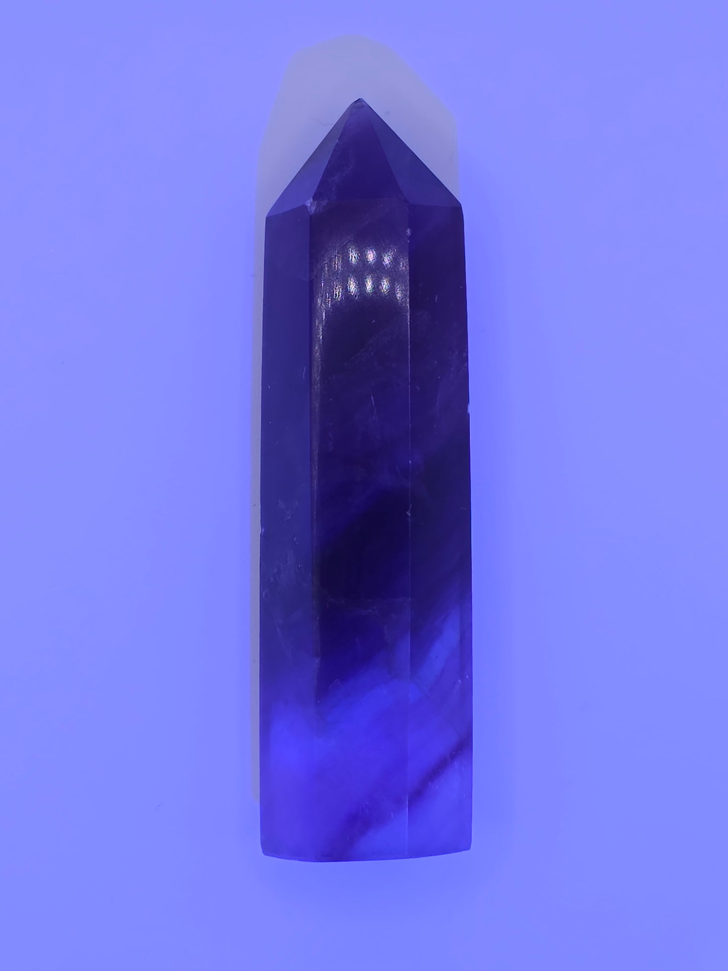 Fluorite tower glowing under UV light with vivid violet tones.