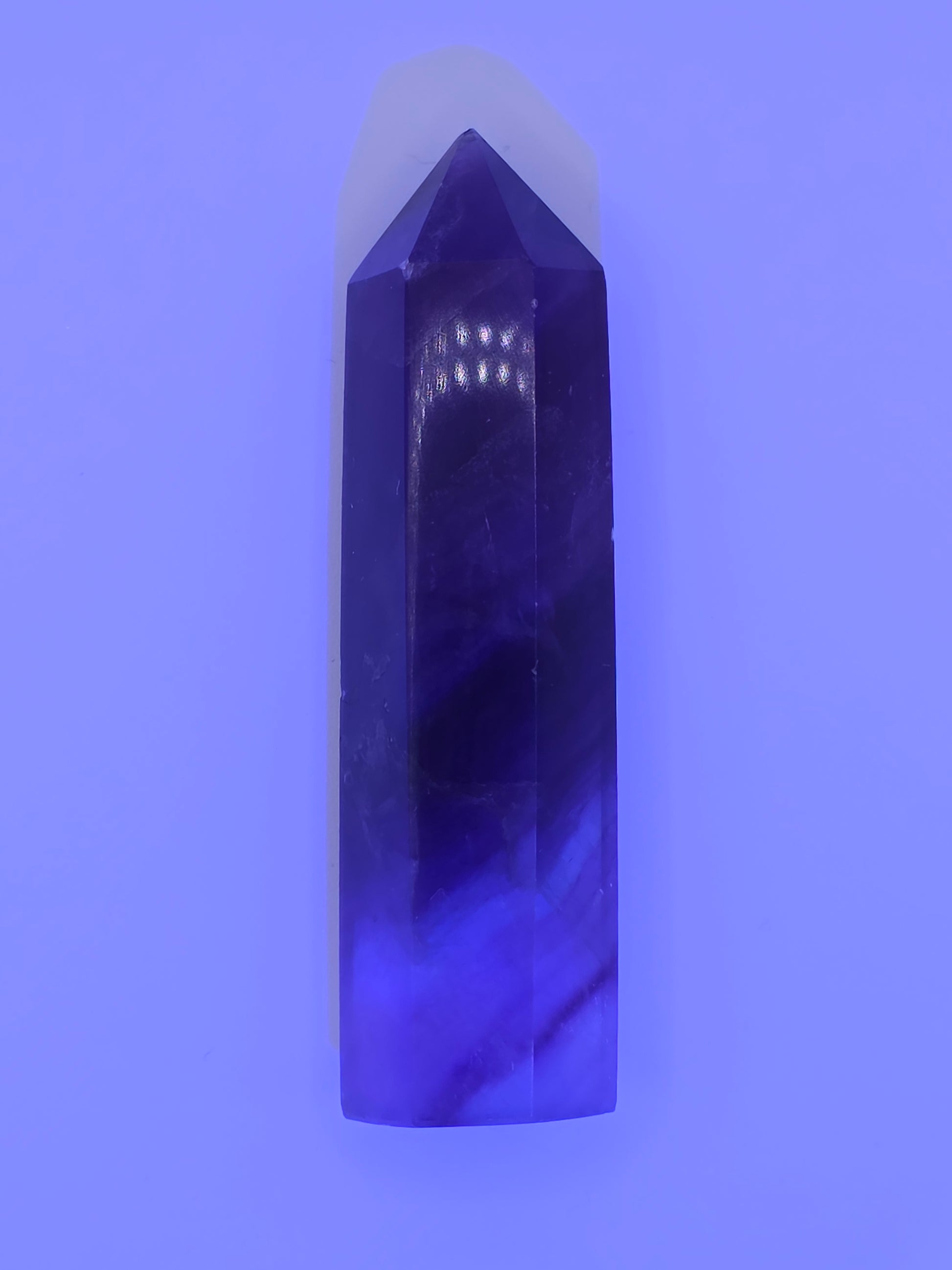 Fluorite tower glowing under UV light with vivid violet tones.