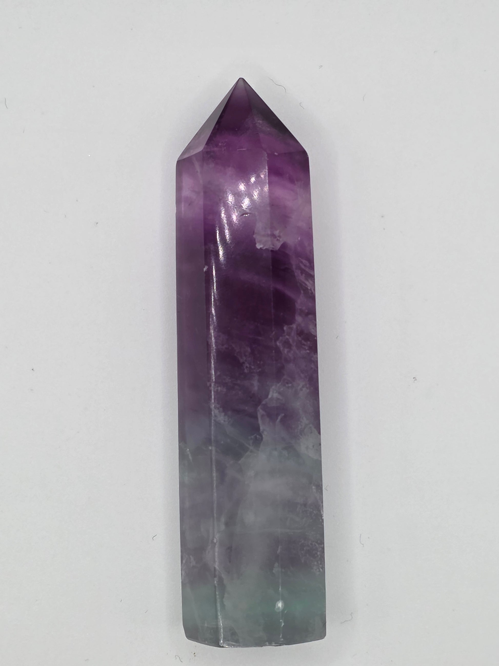 Fluorite tower with purple-to-green banding, polished surface on light background.