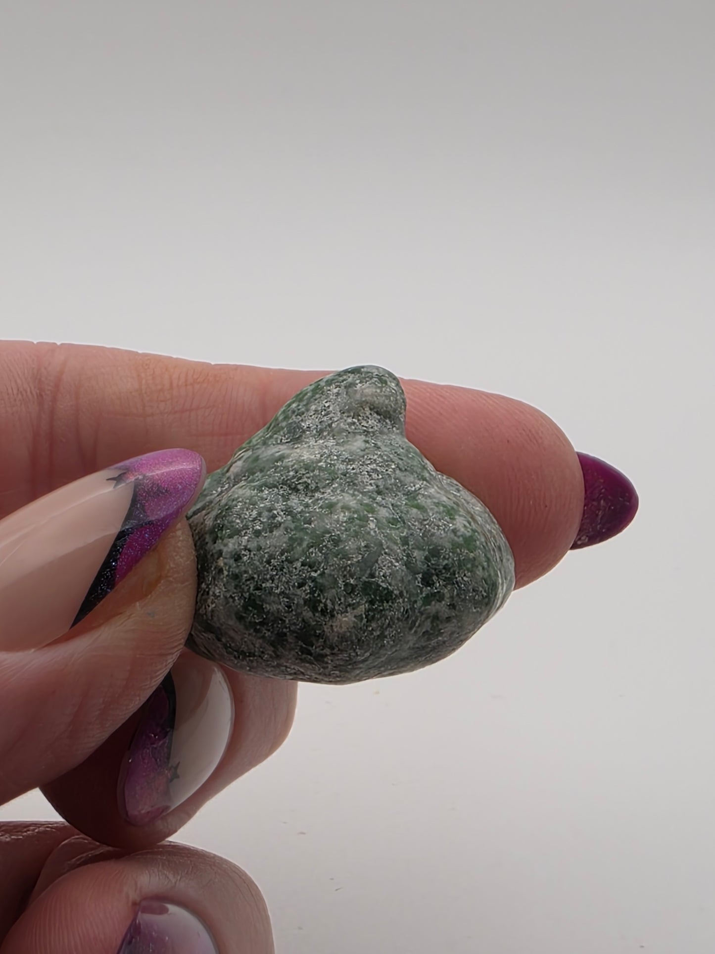 Moss Agate mini pumpkin carving in mottled green and white held in hand.