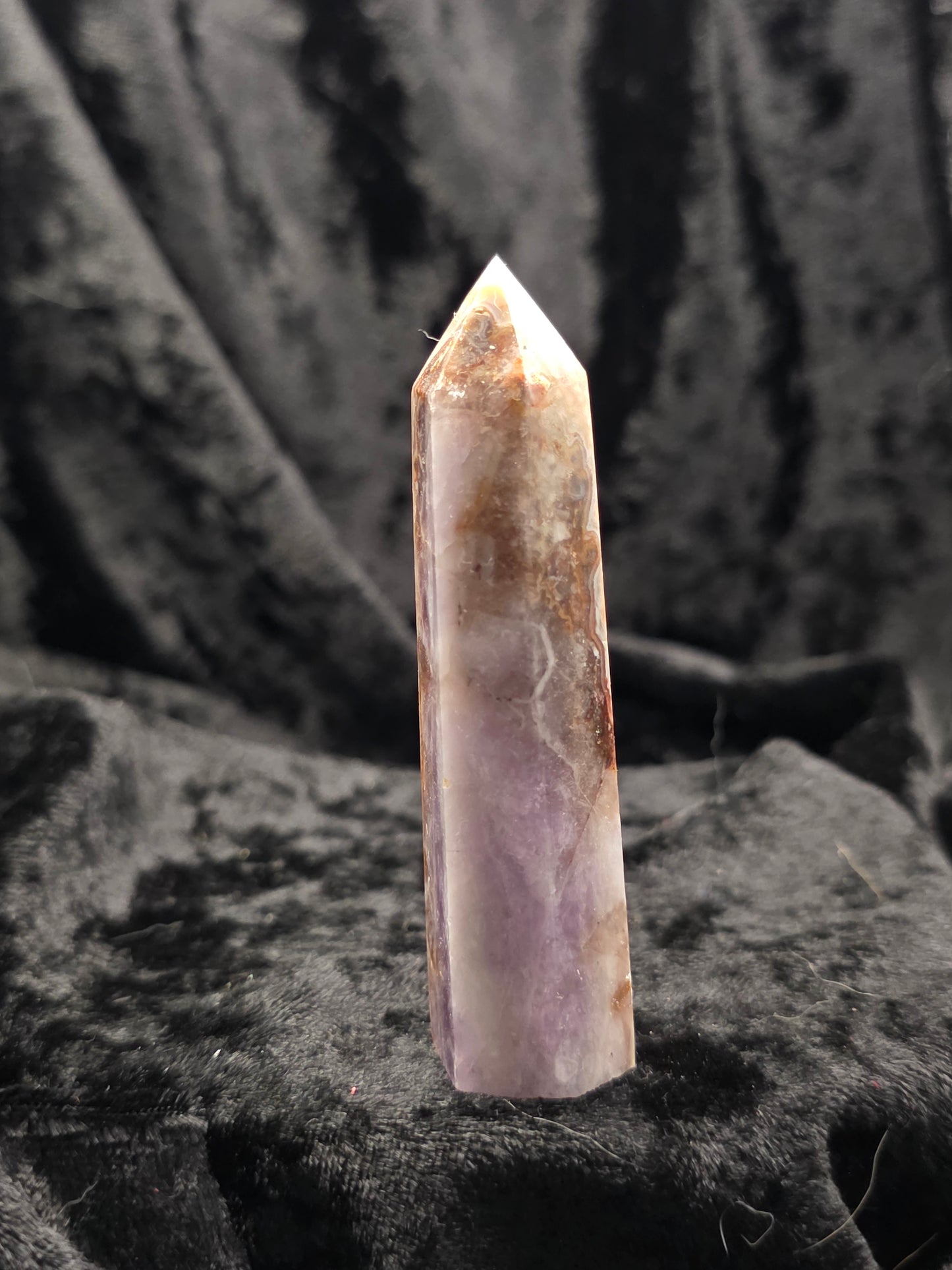 Amethyst & Crazy Lace Agate tower crystal point angled on textured black surface with natural patterns