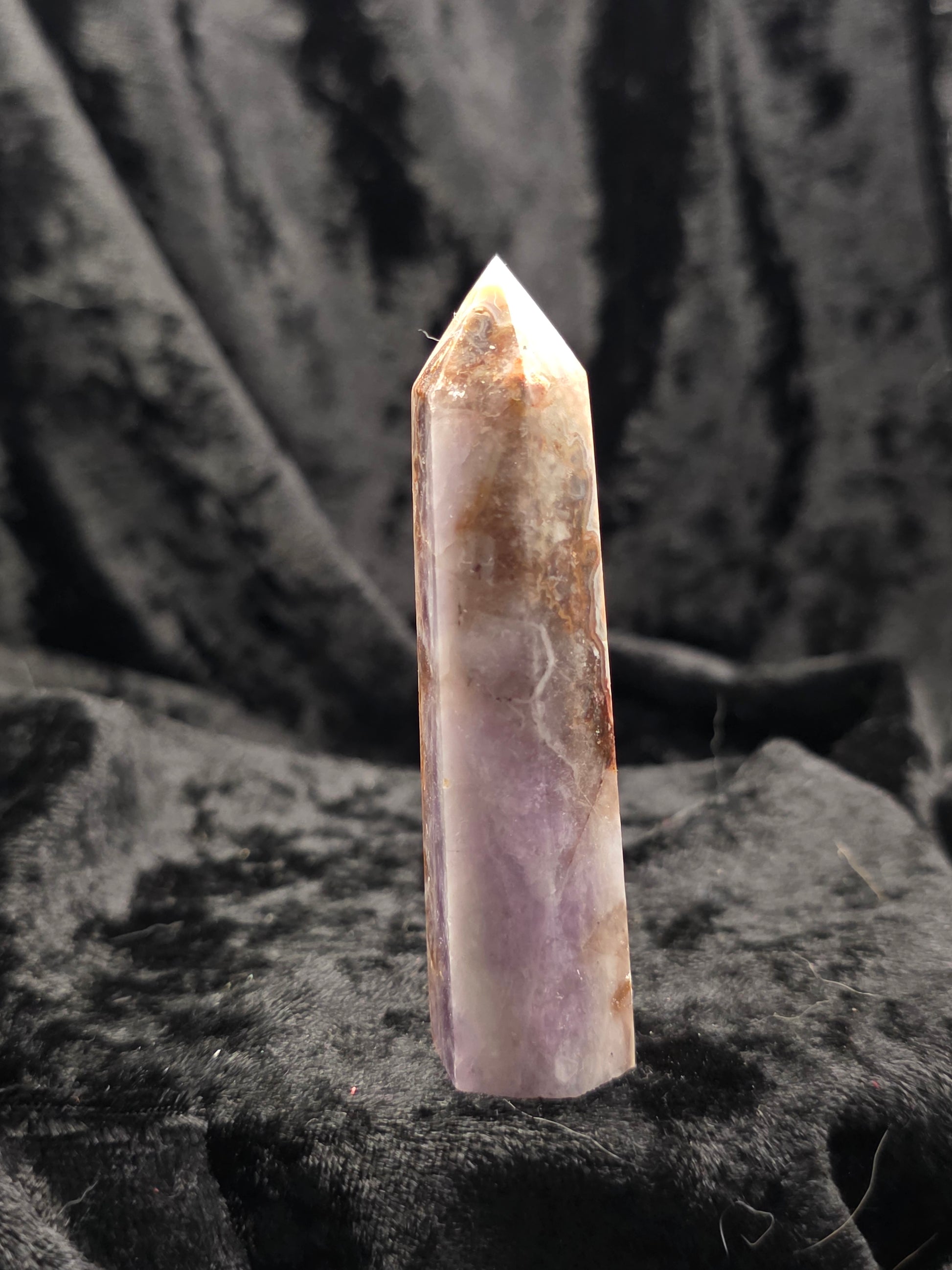 Amethyst & Crazy Lace Agate tower crystal point angled on textured black surface with natural patterns