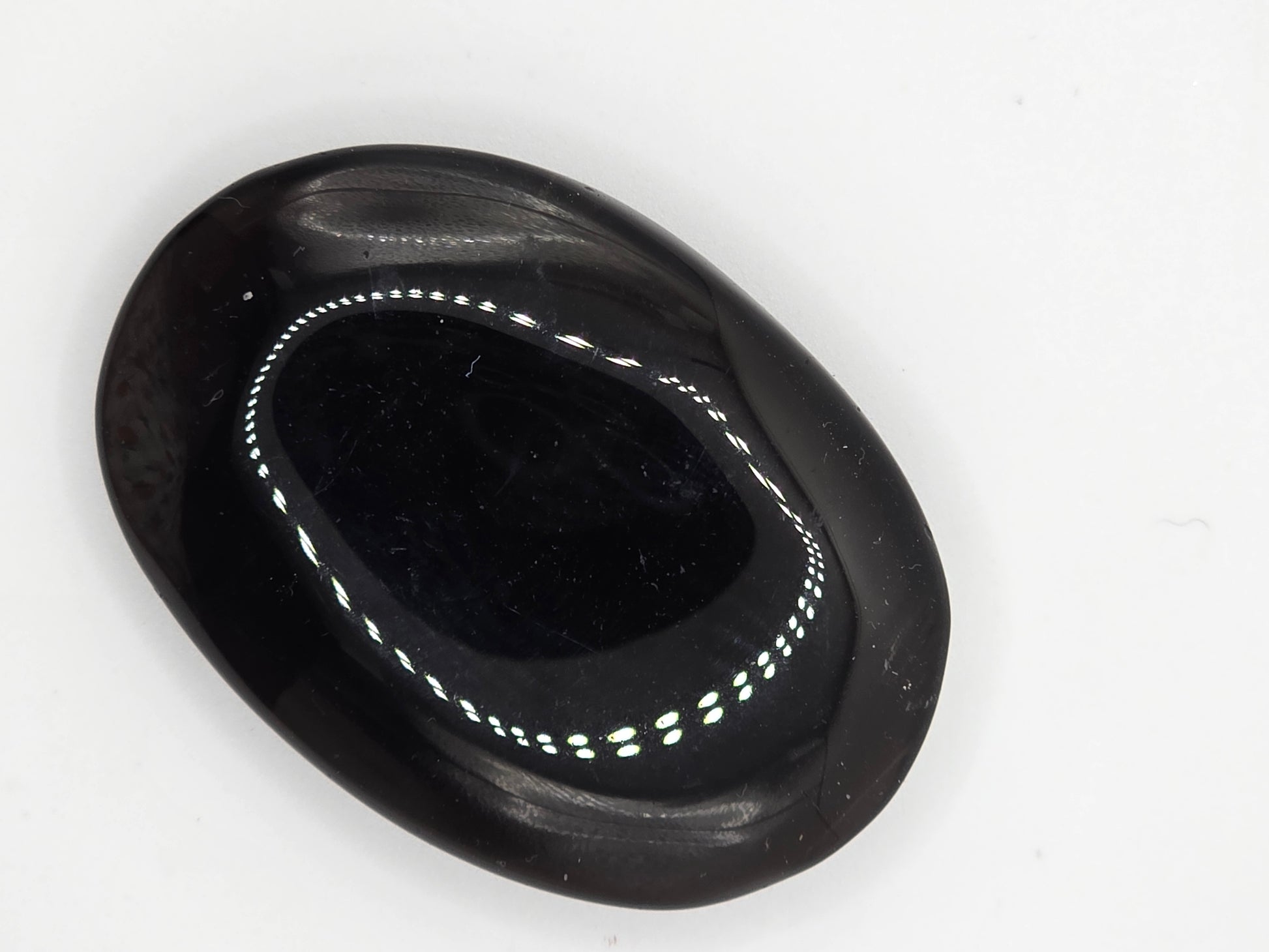 Smoky Quartz palm stone resting on white surface showing soft reflective shine.