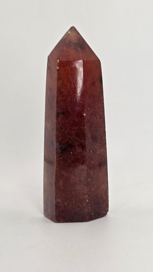 Polished Strawberry Quartz tower with deep berry-red color, translucent facets, natural sparkle, and dark mineral inclusions.