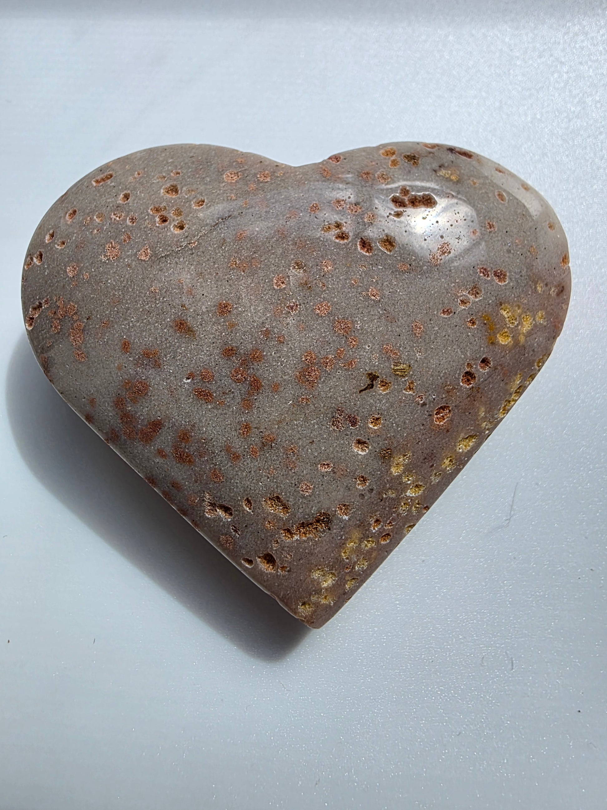 Full view of a Sunstone heart crystal on a white background, featuring metallic copper flecks and smooth polish.